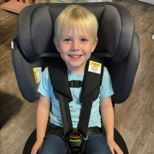 A boy is sitting in a TinySeats Two. The harness is buckled and he is using TinySeats Belt Collector. 