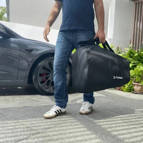 Man is carrying a TinySeats Shoulder Bag in his hand. The scene is a driveway.