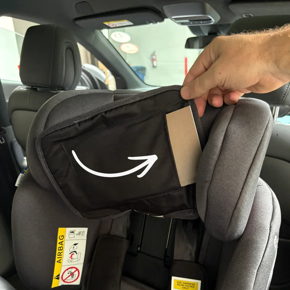 Hand holding up flap on headrest to showcase where the installation guide is hidden on a TinySeats Two