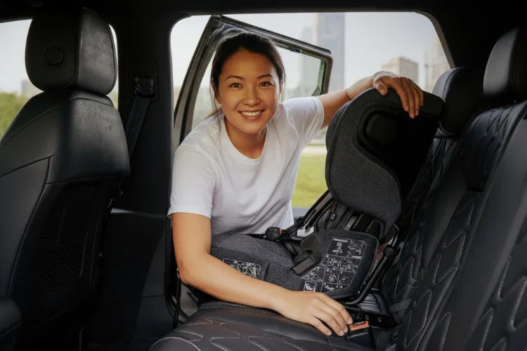 Woman installing an isofix carseat in a vehicle