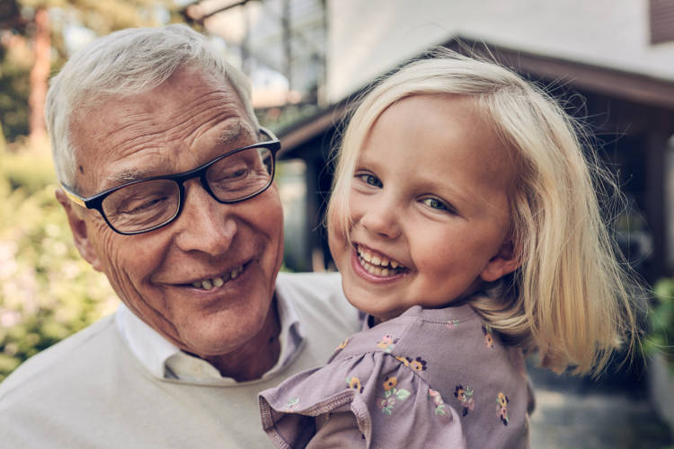 Granddad holding his granddaughter in his arms and both are smiling.