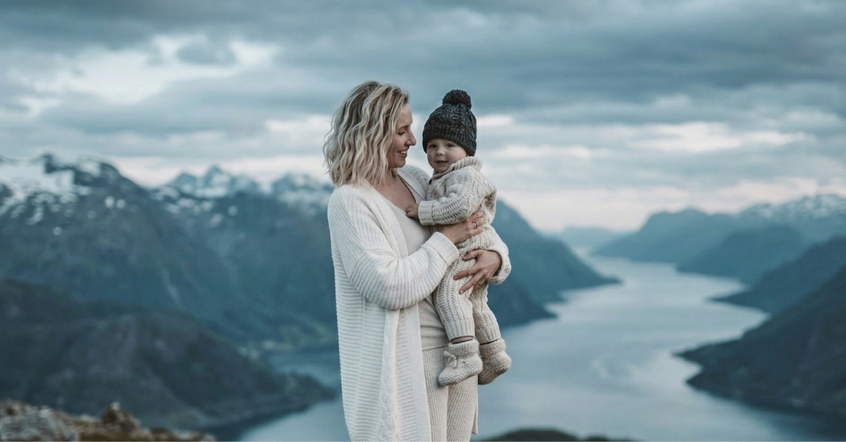 Woman holding a child against a mountainous background