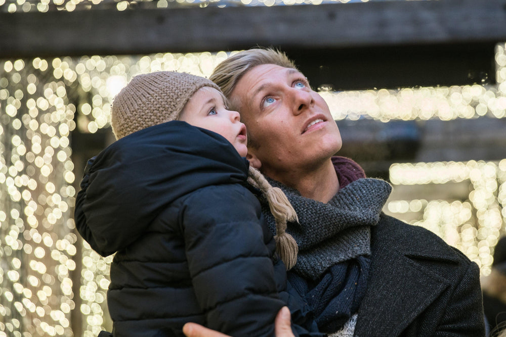 Father holding his young son in his arms in a winter setting, both looking upwards