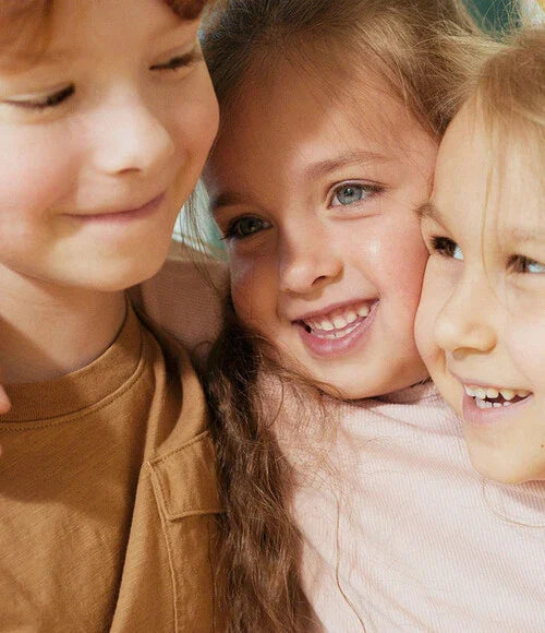 Three children smiling closely together