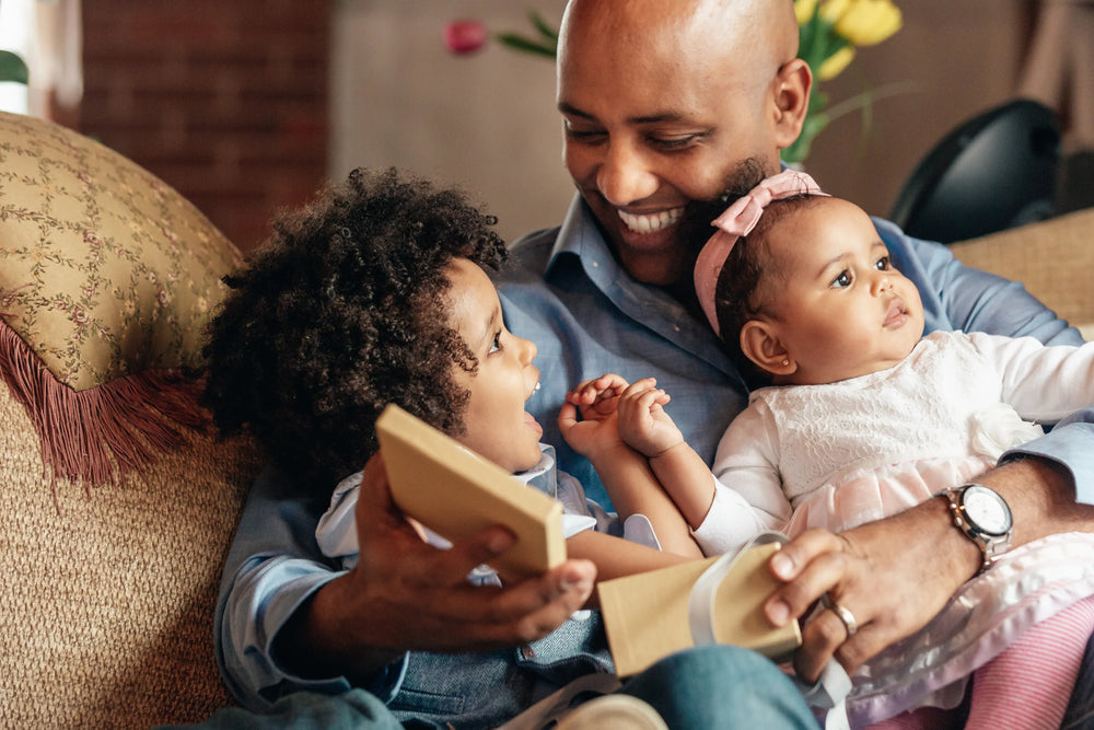 man sitting in a sofa with a toddler boy and baby girl